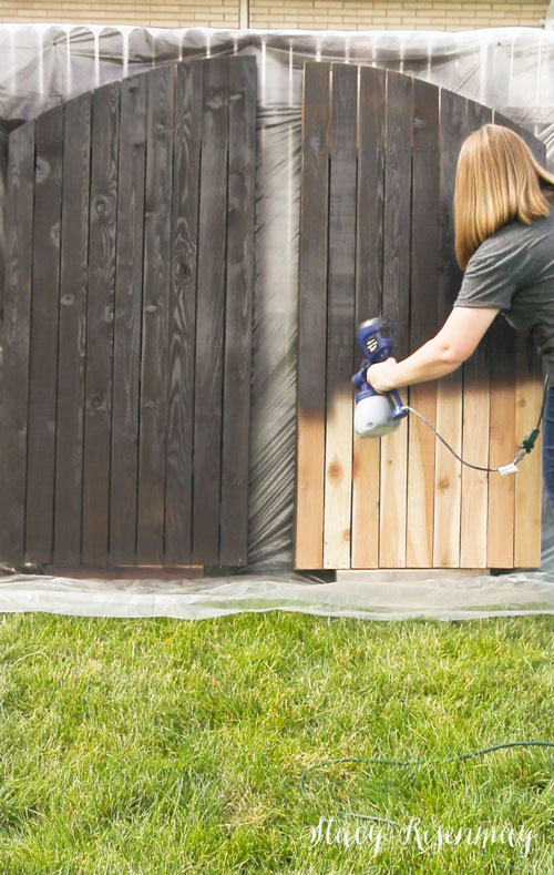 staining a backyard gate with a sprayer