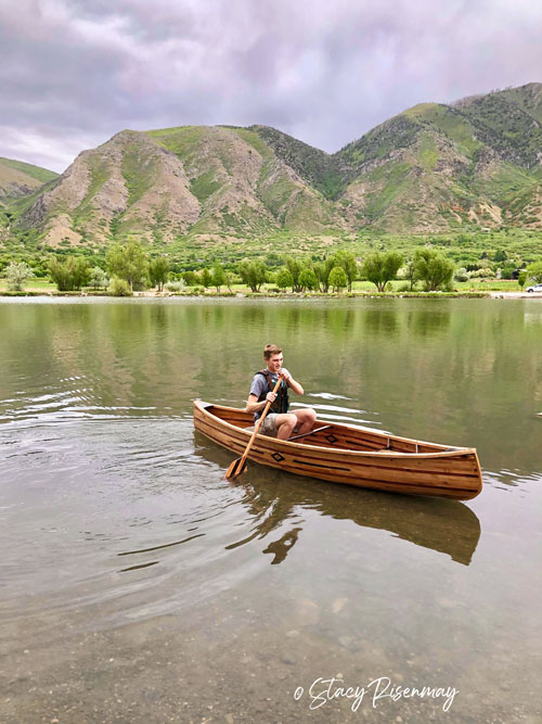 boy in wood canoe on a lake