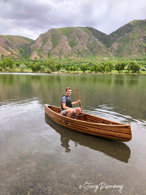 boy sitting in wood canoe on the lake